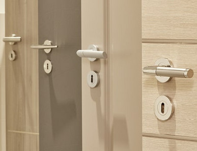 Mehrere nebeneinander angeordnete Türblätter in unterschiedlichen Farbtönen (weiß, holzähnlich, grau) mit integrierten Türgriffen.