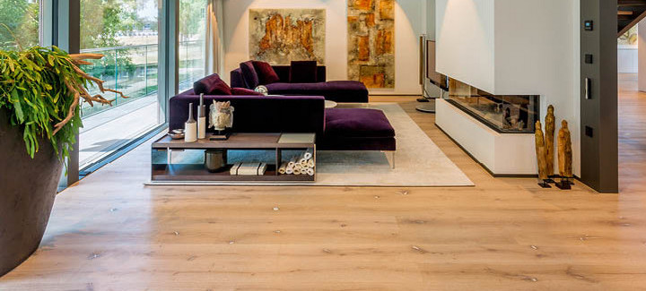 Ein Wohnzimmer mit moderner Einrichtung und einem Kamin, dessen Boden mit Eichen-Rustikal-Laminat verlegt ist.