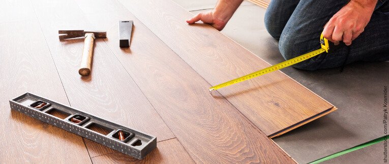 Handwerker verlegt Holzfußboden – Symbol für professionelle Montage- und Verlegeservices.